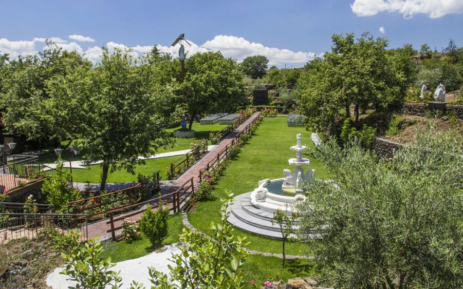 Giardino dell'Oratorio della Madonna delle Grazie con la statua su piedistallo e la fontana in pietra bianca